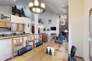 Eine geräumige Küche mit Holzausstattung, ein Essbereich mit Holztisch und ein gemütlicher Wohnraum mit Kamin.