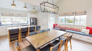A spacious kitchen with a large dining table, modern appliances, and a view of the outdoors. - Beautiful Oceanview home with outdoor grill and spacious rooftop (Pismo Beach)