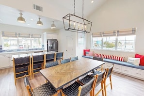 A spacious kitchen with a large dining table, modern appliances, and a view of the outdoors. - Beautiful Oceanview home with outdoor grill and spacious rooftop (Pismo Beach)