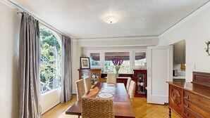 A dining area with a wooden table, woven chairs, and a view of the outdoors. - The Avenue: Charming hideaway with private deck & peeks of ocean, near downtown (Ventura)