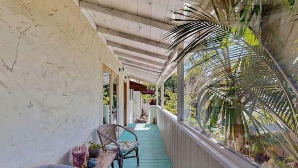 A covered porch with a wooden floor, wicker chairs, a small table, and potted plants. - The Avenue: Charming hideaway with private deck & peeks of ocean, near downtown (Ventura)