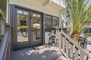 A building with a dark-colored entrance door, a small outdoor seating area with a table and chairs, and a potted plant. - Coastal retreat with patio, sun deck, & kitchenette - 2-minute walk to beach (Santa Barbara)