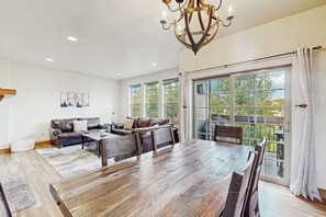Ein großzügiges Wohnzimmer mit einem großen Holzesstisch, einem Ledersofa und einer Chandelier.