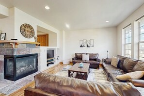 Ein geräumiges Wohnzimmer mit Kamin, Ledersofas, einem Couchtisch und Kunstwerken an den Wänden.