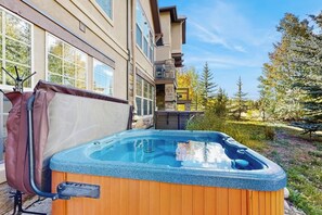 Ein Whirlpool in einem Garten mit einem Haus und Bäumen.