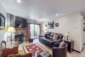 Ein Wohnzimmer mit Kamin, einer Ledersofa, einem Holztisch und einem roten Teppich.