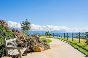 Ein Weg, der zu einer Bank mit Blick auf das Meer und die Berge führt.