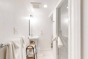 Ein modernes Badezimmer mit einer Duschkabine aus Glas, einem weißen Waschbecken und einem Handtuchhalter.