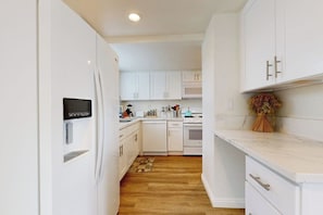 A modern kitchen with white cabinetry, a built-in oven, and a microwave. - Dog-friendly two-story home with two kitchens, fast WiFi, patio, & gas grill (Newport Beach)