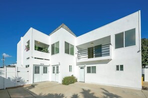 A modern two-story building with a white exterior, large windows, and a small balcony. - Dog-friendly two-story home with two kitchens, fast WiFi, patio, & gas grill (Newport Beach)