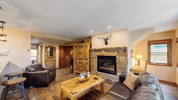 A living room with a stone fireplace, leather furniture, and a wooden coffee table. - Lovely Townhouse in Prime Location w/Shared Pool, Hot Tub - Near Downtown/Lifts (Breckenridge)