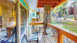A balcony with wooden railings, a stone wall, and a view of a building with balconies. - Lovely Townhouse in Prime Location w/Shared Pool, Hot Tub - Near Downtown/Lifts (Breckenridge)