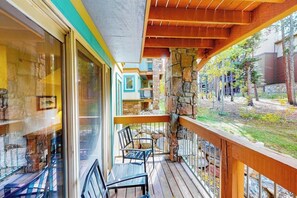 A balcony with wooden railings, a stone wall, and a view of a building with balconies. - Lovely Townhouse in Prime Location w/Shared Pool, Hot Tub - Near Downtown/Lifts (Breckenridge)