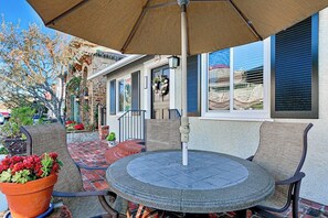 Une terrasse extérieure avec une table ronde, des chaises et un grand parasol.