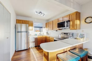 Eine moderne Küche mit Holzschränken, Edelstahlgeräten und einer zentralen Kochinsel mit Sitzgelegenheiten.