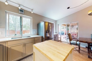 A kitchen with a large window, a refrigerator, and a dining area with a table and chairs. - Inviting home with private hot tub, amazing deck & prime location (Carbondale)