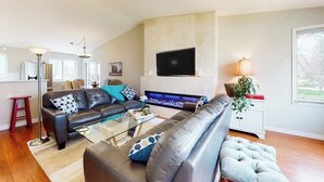Ein modernes Wohnzimmer mit einer Couch, einem Couchtisch und einem an der Wand befestigten Flachbildfernseher.