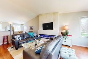 A modern living room with a sofa, coffee table, and a flat-screen TV mounted on the wall. - Inviting home with private hot tub, amazing deck & prime location (Carbondale)