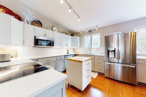 A modern kitchen with white cabinetry, stainless steel appliances, and a central island. - Inviting home with private hot tub, amazing deck & prime location (Carbondale)