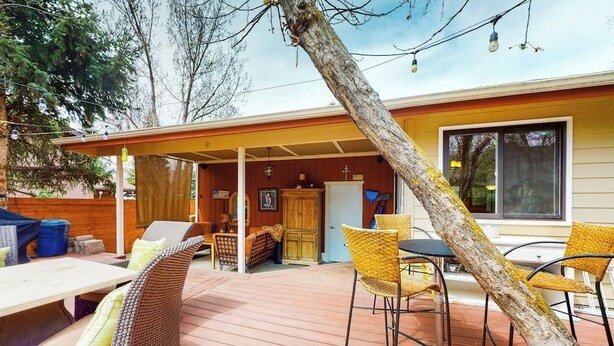 Eine überdachte Terrasse im Freien mit Korbmöbeln, einem Tisch und Stühlen.