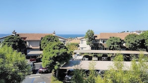 Zona residencial amb cases, cotxes aparcats i una vista clara del mar.