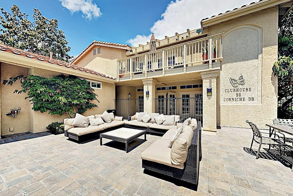 A courtyard with a lounge area, outdoor seating, and a balcony.