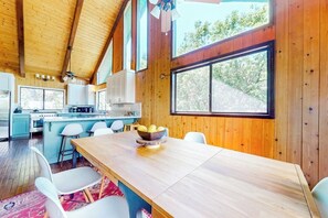A wooden interior with a kitchen, dining area, and large windows. - 3BR/2.5BA home with views, yard, BBQ, game room, fireplace & EV charger (Lake Arrowhead)