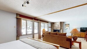 Une chambre avec un grand lit, un canapé, une télévision et un mur en pierre.