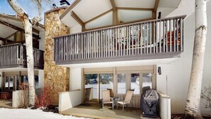 Un bâtiment moderne à deux étages, doté d’un balcon, d’un pilier en pierre et d’un espace extérieur aménagé et couvert.