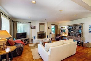 A living room with a fireplace, a television, a sofa, a coffee table, and a bookshelf. - Charming, Single-Level Home w/ Fast WiFi, Gas Fireplace, & a Furnished Patio (Santa Barbara)