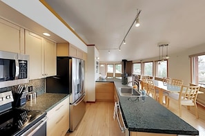 Eine moderne Küche mit Edelstahlgeräten, Holzschränken und einer großen Kochinsel mit Sitzgelegenheiten.