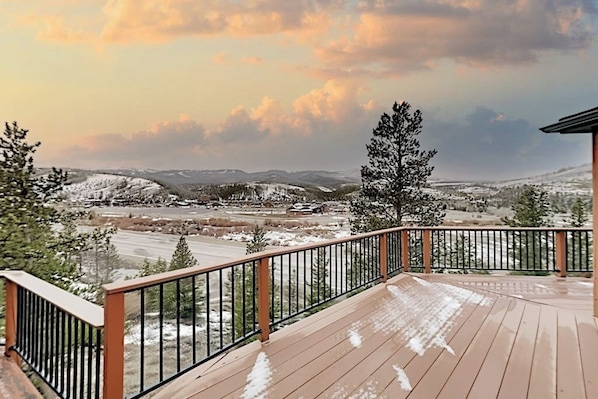 Eine Holterrasse mit Geländer, die auf eine verschneite Landschaft mit Bergen in der Ferne blickt.