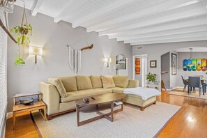 Ein modernes Wohnzimmer mit einer Couch, einem Couchtisch und hängenden Pflanzen.