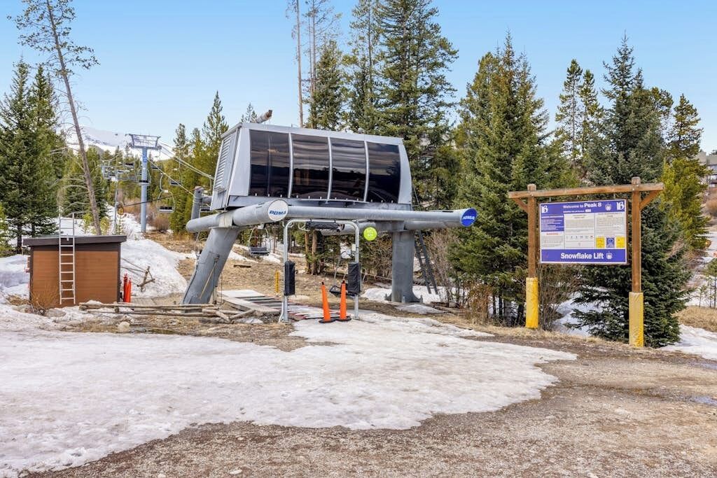 A ski lift structure with a sign indicating 'Snowflake Lift' and a wooden signboard with information.
