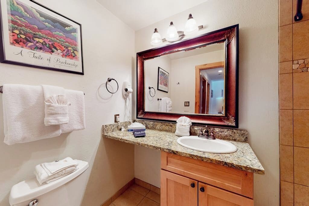 A bathroom with a sink, mirror, towel rack, and toilet.