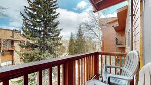 A balcony with wooden railings, a table, and two chairs. - Dog-friendly ski condo with hot tubs, grills, & gym (Breckenridge)