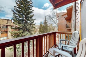 Ein Balkon mit Holzgeländern, einem Tisch und zwei Stühlen.