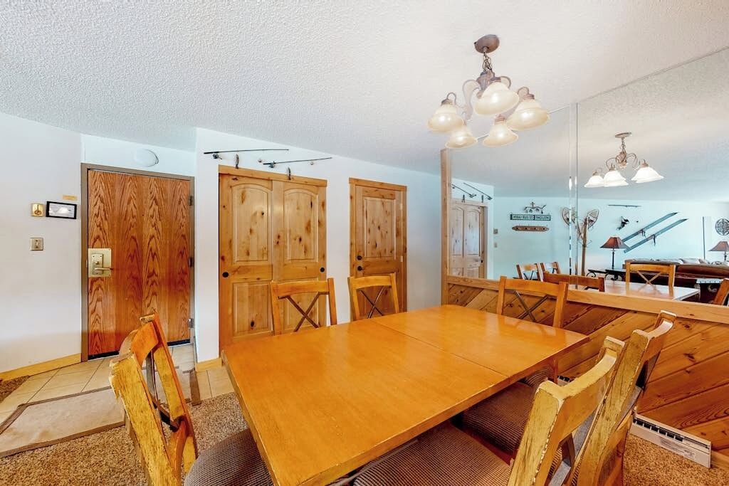 A dining area with a wooden table and chairs, wooden cabinets, and a chandelier.
