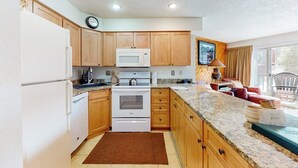 A kitchen with wooden cabinets, a microwave, stove, and a large window. - Dog-friendly ski condo with hot tubs, grills, & gym (Breckenridge)