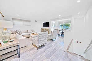 Ein geräumiger Wohnbereich mit Sofa, Sesseln, Couchtisch und Fernseher.