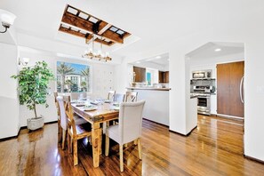 Eine moderne Küche mit Holzausstattung, einem Einbauofen und einem Essbereich mit Holztisch und Stühlen.