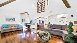 Ein geräumiges Wohnzimmer mit Holzdielen, zwei Sofas, einem Couchtisch und einem großen Fenster mit Blick.