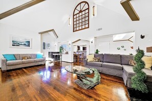 Ein geräumiges Wohnzimmer mit Holzdielen, zwei Sofas, einem Couchtisch und einem großen Fenster mit Blick.