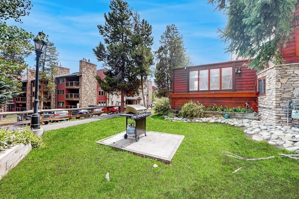 Une cour avec un barbecue, des bâtiments en pierre et une structure en bois rouge.