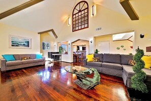 Ein geräumiges Wohnzimmer mit Holzböden, zwei Sofas, einem Couchtisch und einem großen Fenster.