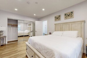 A bedroom with a large bed, a wardrobe, a mirror, and butterfly wall art. - Classic dog-friendly home with fast WiFi, full kitchen, & A/C - near beaches (Newport Beach)