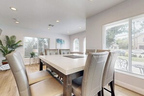 A dining room with a large table and six chairs, a potted plant, and a window with blinds. - Classic dog-friendly home with fast WiFi, full kitchen, & A/C - near beaches (Newport Beach)