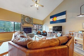 A living room with leather sofas, a fireplace, a television, and a large window. - Cozy 3rd-floor condo w/ hot tubs, fireplace, balcony, gym, & views (Breckenridge)