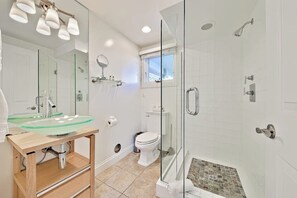 A modern bathroom with a glass shower enclosure, a glass sink, and a toilet. - Beautiful oceanfront with deck & private road (Dana Point)