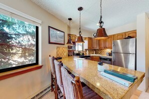 A kitchen with a granite countertop, stainless steel appliances, and wooden cabinets. - Upgraded ski condo with fireplace, hot tubs, & gym (Breckenridge)